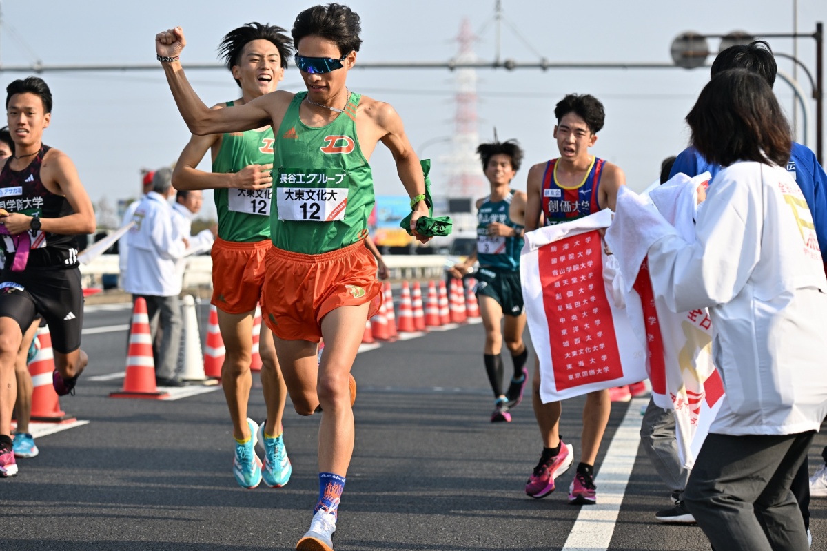 1区・佐竹勇樹選手から襷を受け取る2区・西川千青選手（中央）　Ⓒ月刊陸上競技