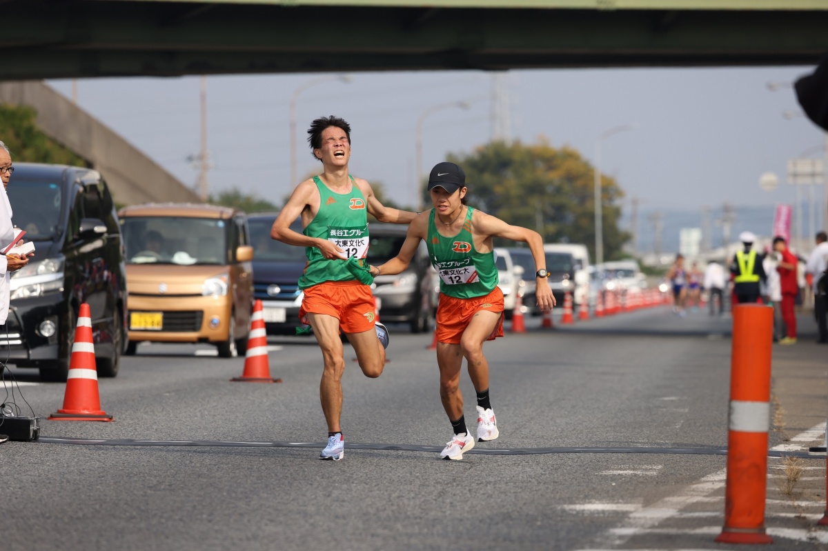 3区・久保田徹選手（左）から4区・入濵輝大選手（右）への襷渡し　Ⓒ月刊陸上競技