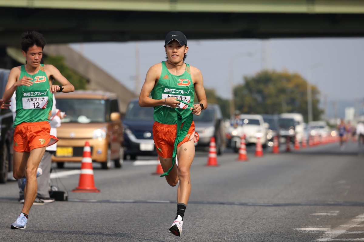 3区久保田徹選手（左）から襷を受け取り走り出す4区・入濵輝大選手（右）　Ⓒ月刊陸上競技